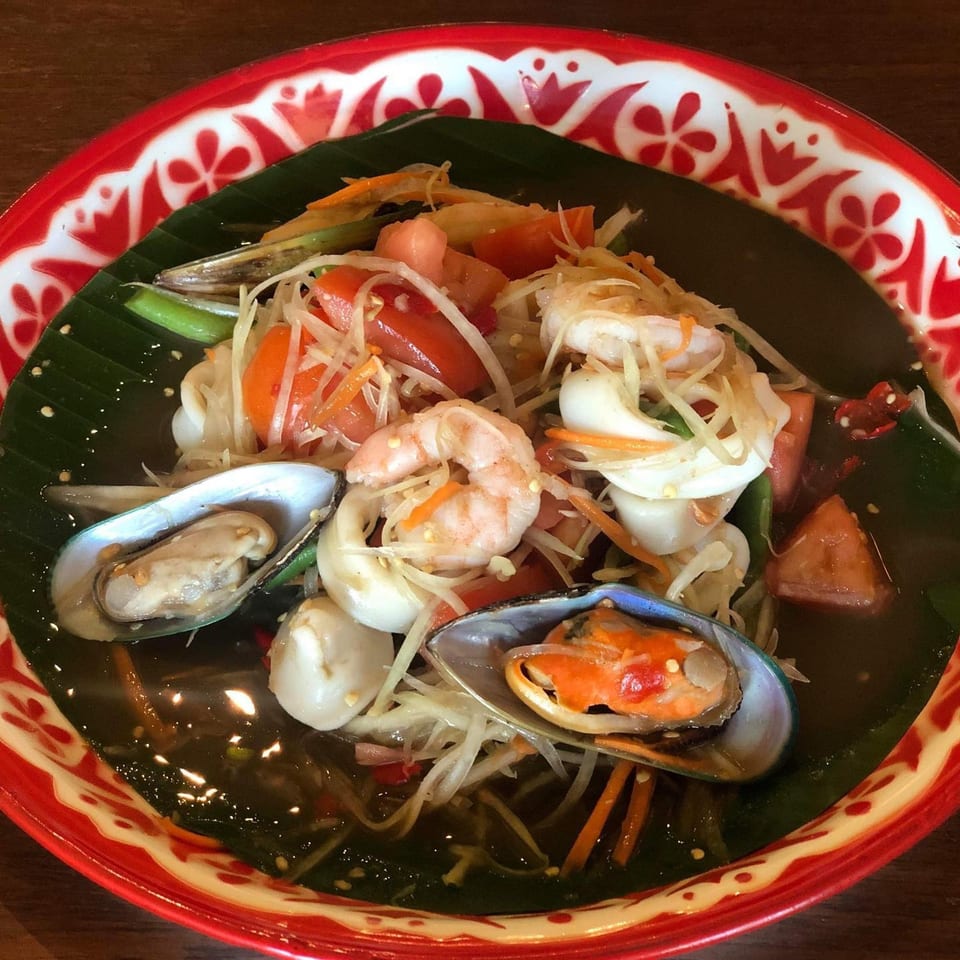 Tamarind Thai Cuisine's papaya salad with shrimp, squid, mussels, and vegetables in a red patterned bowl.